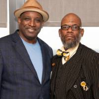 2 men pose for picture at event